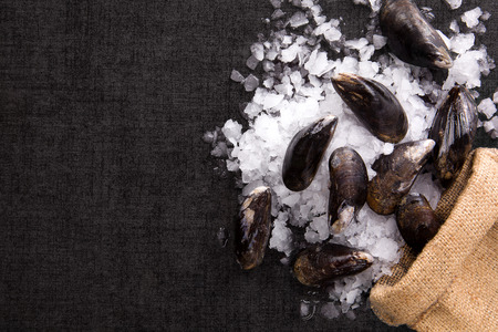 Shells on ice on brown burlap bag, flat lay. Luxurious seafood background top view.の写真素材