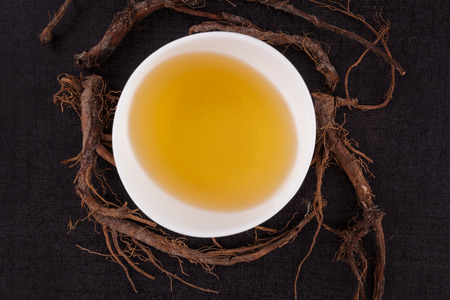 Dandelion tea and dandelion roots, isolated on black background from above. Alternative medicine, natural remedy.の写真素材