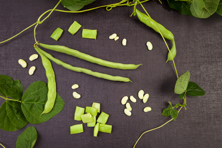 Raw green string beans, whole and sliced, black surface. Healthy legumes eating.
