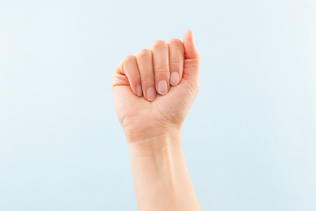American sign language. Female hand showing letter A isolated on blue background. の写真素材