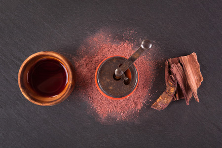 Psychoactive ayahuasca drink, mimosa hostilis powder and bark from above on dark surface.