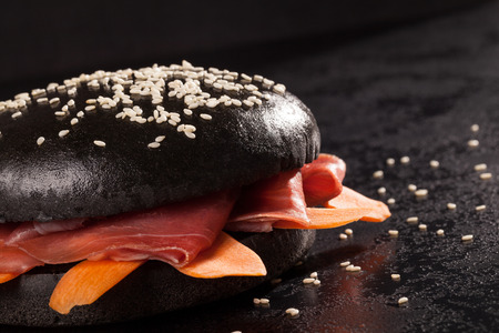 Japanese Black Burger with ham and carrot on dark background. Culinary hamburger.の写真素材