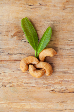 Cashew nuts with leaves on wooden table from above.の写真素材