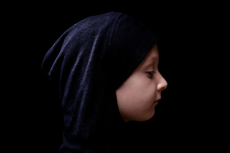 Little muslim girl in black hijab isolated on black background. Islam religion.の写真素材