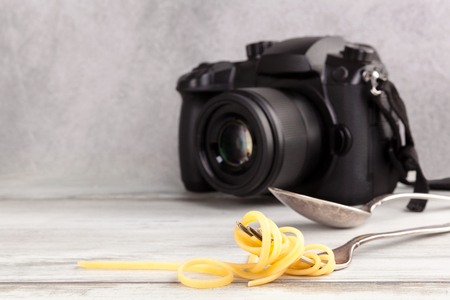 Spaghetti on fork and dslr camera on wooden table. Food photography concept.の写真素材