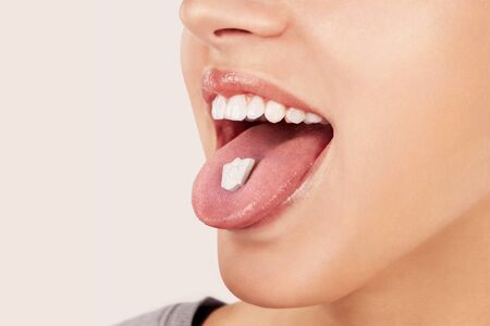 Sexy girl with Ecstasy pill on tongue. MDMA assisted therapy, alternative medicine.