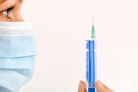 Beautiful doctor with mask and syringe isolated.の写真素材
