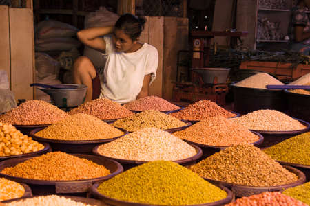 RANGOON, MYANMAR - APRIL 21, 2009: Burmese woman selling different legumes at local market.のeditorial素材