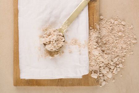 Wholegrain flour and scoop on wooden board from above. Bread making concept.