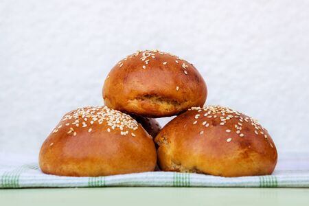 Fresh homemade burger buns with sesame on kitchen towel in sunny day.