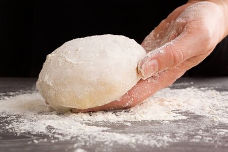 Pizza making. Homemade dough on female hand. Cooking and kitchen background. Bread making.