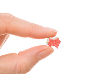 Ecstasy pill in female hand isolated on white backround. MDMA assisted psychedelic therapy.