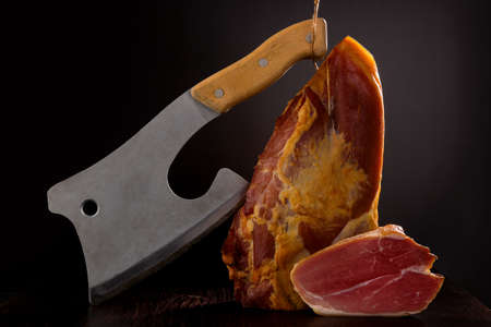 Luxurious meat background. Smoked prosciutto ham with butcher cleaver.
