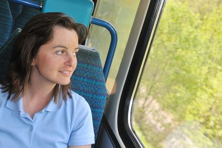 Young woman passanger sitting inside train and looking trough window