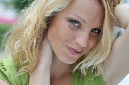 Close up portrait of young beautiful smiling woman with hands holding head - outdoorsの写真素材