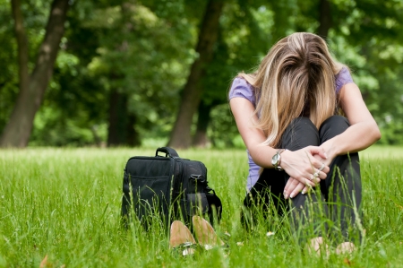 Young depressed business woman siting in grass - notebook bag and shoes lying nextの写真素材