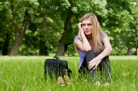 Young worried business woman siting in grass - notebook bag and shoes lying nextの写真素材