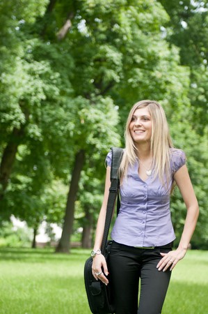 Young business woman wit laptob bag walking outdoors in parkの写真素材