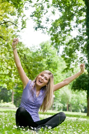 Young happy woman siting in grass with flowers enjoying lifeの写真素材