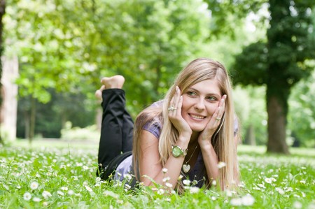 Young smiling woman lying in grass during sunny day (park - outdoors)の写真素材
