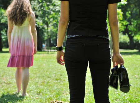 One woman stands turned back to her friend who holds shoes in handの写真素材