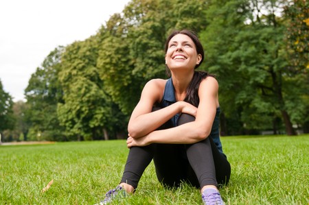Young happy smiling woman looking up siting in grassの写真素材