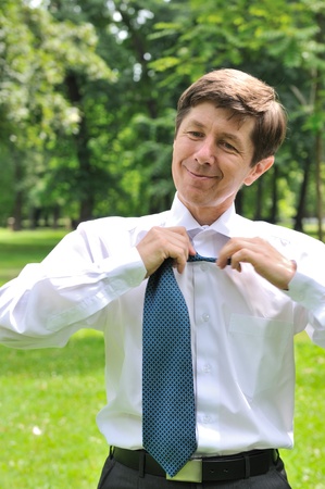 Escape from civilization - senior business man loosening tie in fresh green parkの写真素材