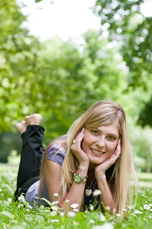 Young smiling woman lying in grass during sunny day (park - outdoors)の写真素材