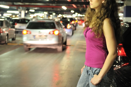 Young woman standing at car in underground parking place                       の写真素材