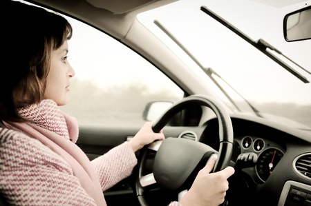 Young woman driving car in rainの写真素材