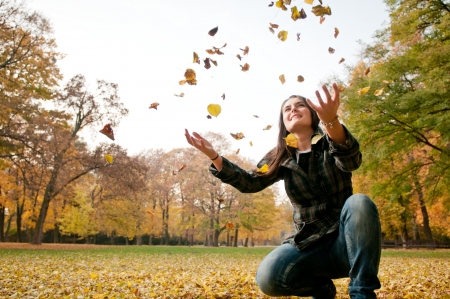 Happy life - woman throwing leaves in fallの写真素材