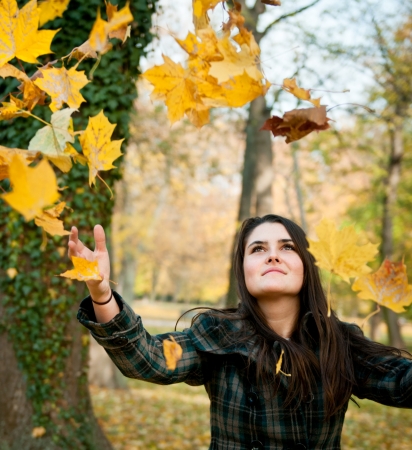 Happy life - woman throwing leaves in fallの写真素材