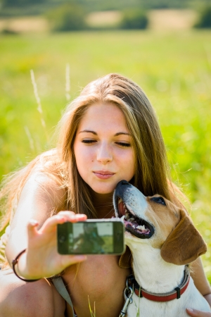 Teen girl taking photo of herself and her dog with mobile phone cameraの写真素材