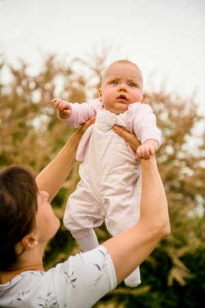 Mother lifting her beautiful baby - outdoor in natureの写真素材