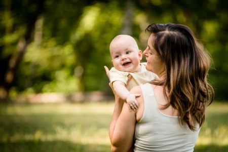 Happy mother holding her baby on hands outdoor in natureの写真素材