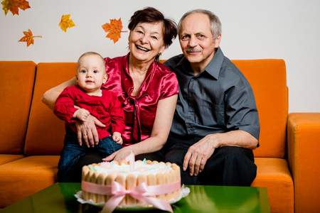 Grandparents with their small grandchild celebrating first birthday at home