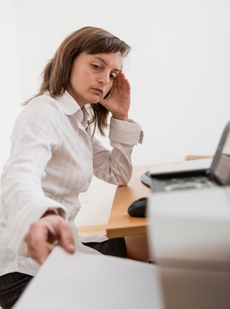Business person in depression reaching hand and taking paper from printer on workplace