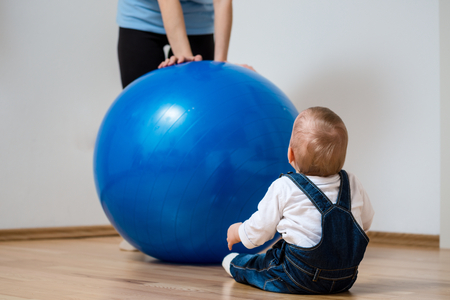 Mother exercises with big blue fit ball and baby - home interiorの写真素材