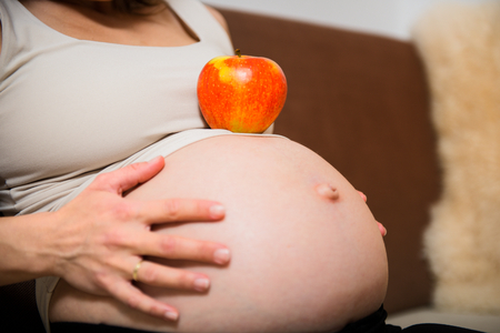 Detail of pregnant belly with appleの写真素材