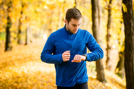 Man jogging in nature and checking pulse