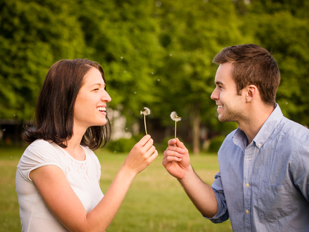Couple blowing dandelionsの写真素材
