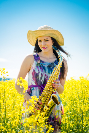 Woman with saxophone in rapeseed fieldの写真素材