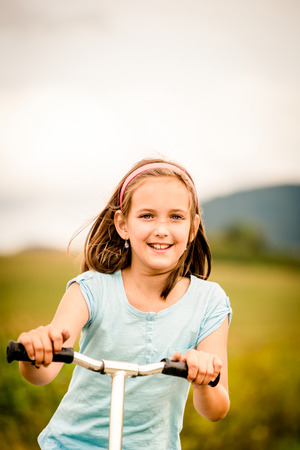 Beautiful girl driving scooter on rural road outdor in natureの写真素材