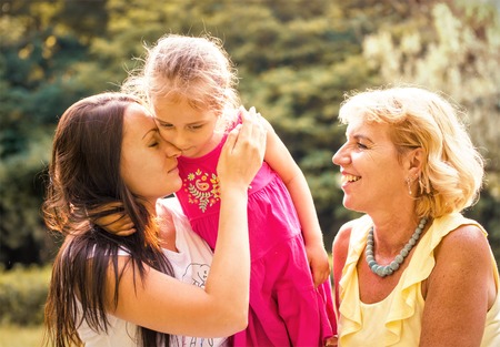 Women generations - mother hugging her child outdoor in natureの写真素材
