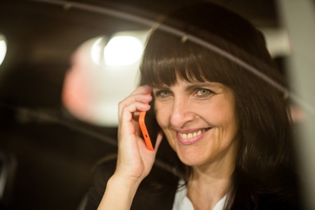 Detail of senior business woman calling mobile phone in car at nightの写真素材