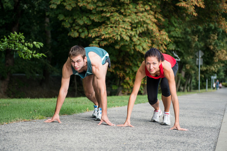 Young sport couple in starting postion prepared to compete and run