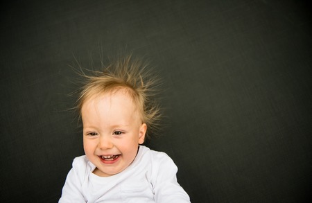 Portrait of smiling baby with standing hair from static electricityの写真素材