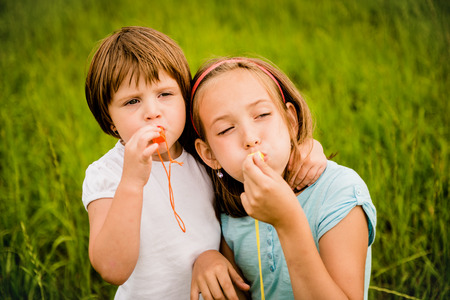 Children blowing together in whistles - outdoor in natureの写真素材