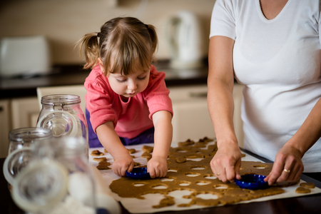 Mother and child cutting out cookies from dough at home kitchenの写真素材