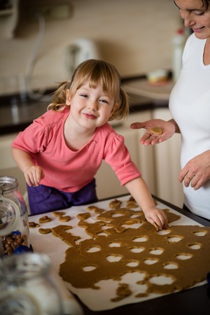 Mother and child cutting out cookies from dough at home kitchenの写真素材
